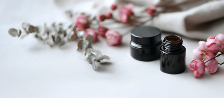 Abstract minimal concept. Black cosmetic empty bottle display and blurred pink flower bud and green leaves. Mock up template for product presentation. copy text spaceの写真素材