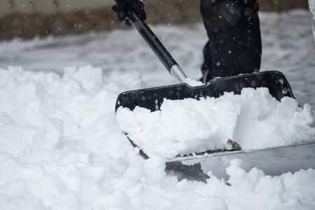Someone is  shoveling snow outside in winter while it is snowingの写真素材