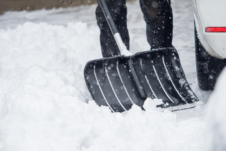 Someone is  shoveling snow outside in winter while it is snowingの写真素材