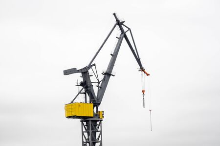 A crane works at the harbor in front of white skyの写真素材