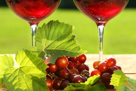 Glasses of  red wine with grapes on a tableの写真素材