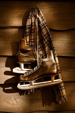 Old hockey skates with scarf hanging on a wall/ Sepia tone filterの写真素材