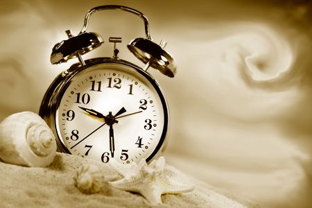 Alarm clock showing time on the beach with seashells/Sepia toneの写真素材