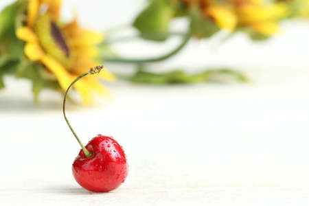 One little cherry with sunflowers in backgroundの写真素材