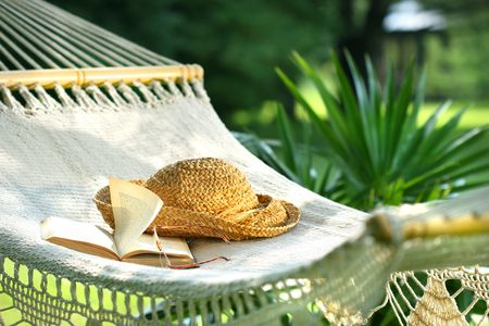 Hammock, book, hat, and glasses on a sunny summer dayの写真素材