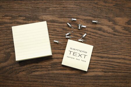 Yellow sticky note pads with silver push pins on oak wood/ Sepia tone