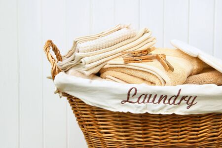 Clean towels in wicker basket with white wood backgroundの写真素材