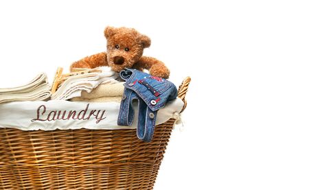 Laundry basket full of towels with teddy bear on white backgroundの写真素材
