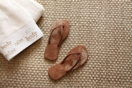 Flip flops with fluffy towels on seagrass rugの写真素材