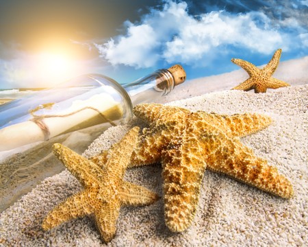 Message in a bottle buried in sand on a beachの写真素材