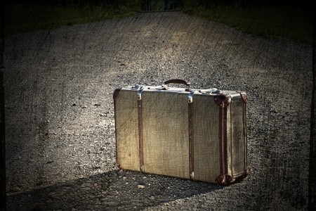 Old suitcase left on a dirt roadの写真素材