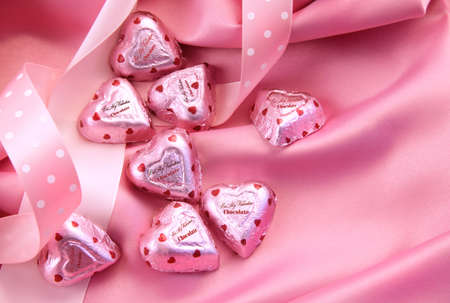 Valentine's chocolate hearts on pink satin with ribbons