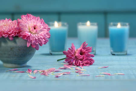 Pink chrysanthemum flowers in bowl of water with candlesの写真素材