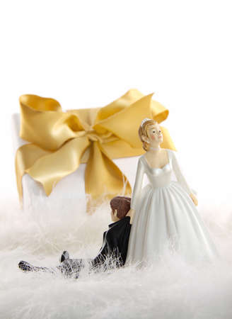Wedding cake figures with gold ribbon gift on whiteの写真素材