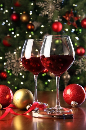 Glasses of red wine in front of Christmas tree for the holidaysの写真素材