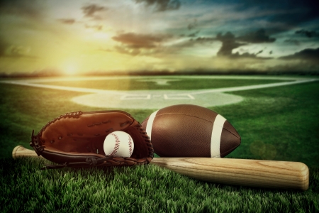 Baseball, bat, and mitt with field in background at sunsetの写真素材