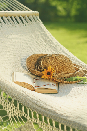 Straw hat and book on lace hammockの写真素材