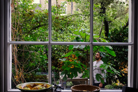 Look through a window of a mid aged man looking up outside