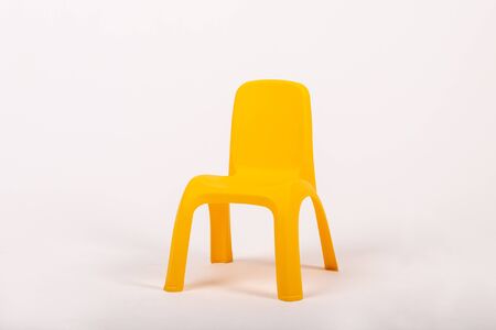 small yellow plastic childrens chair on a white backgroundの写真素材