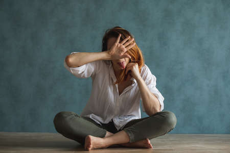 a girl, a woman covers her face with her handsの写真素材