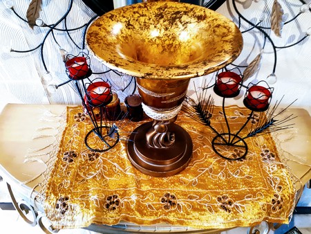 An oriental-style home furniture consisting of a stylish vase, surrounded by two chandeliers and an iron mirror frame, and sitting on a decorative wooden chair.の写真素材