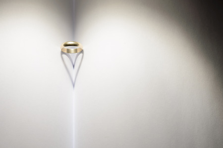 Ring forming a heart of shadow on a book. This image represents unity, love and closeness between a couple. It has empty space so it can be used as background in compositions.の写真素材