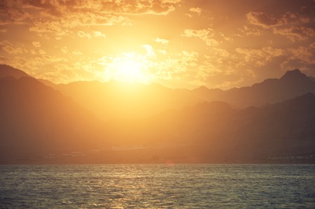 Mountains and sea at sunsetの写真素材