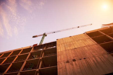 building of a skyscraper by cranes at sunsetの写真素材
