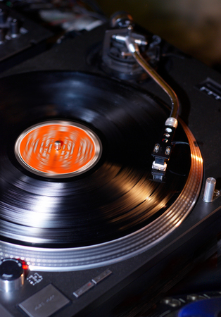 Dj turntables needle cartridge on black vinyl record with music. Close up, focus on turntable and audio disc recordの写真素材
