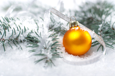Christmas beautiful yellow ball with fir branch and snow on white backgroundの写真素材