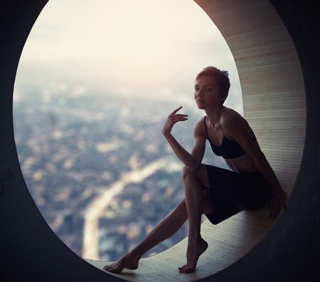 Beautiful young adult slim pretty and attractive sensuality woman in elegance fashionable skirt in a round windowの写真素材