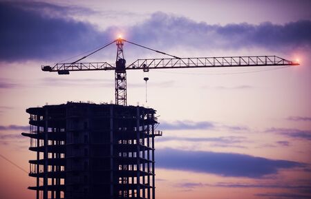 construction of a building by cranes at night