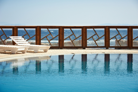 Fence of the resort pool reflected on the water. Pure blue sky on the background.の写真素材