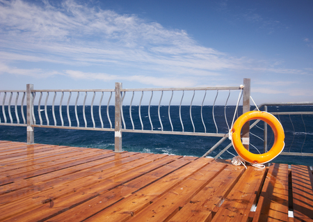 Red lifebuoy with rope on a wooden pier