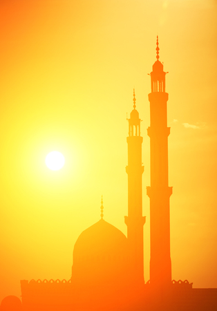 Mosque silhouette at sunset, with sun flare.の写真素材