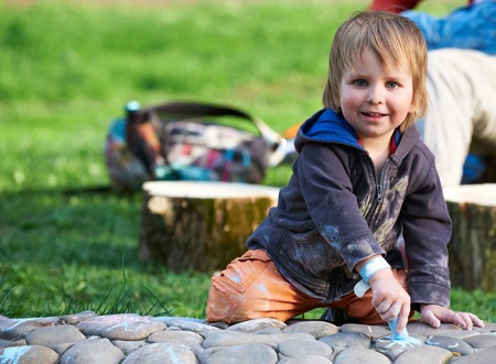 Little boy drawing with sidewalk chalk in the park.の写真素材