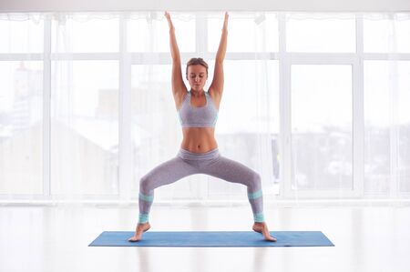 Beautiful young woman practices yoga asana Stupasana at the yoga classの写真素材