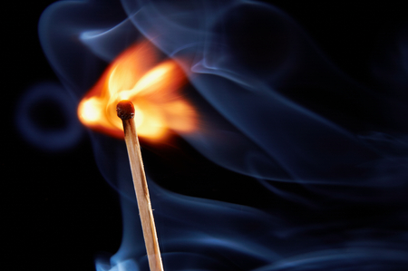 burning match with smoke on black backgroundの写真素材