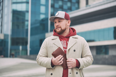 Young business man in casual clothes with leather notepad near of modern building.の写真素材