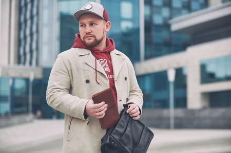 Young business man in casual clothes with leather notepad near of modern building.の写真素材