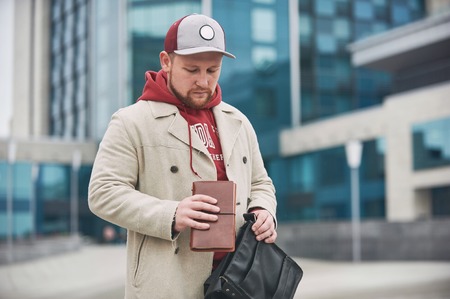 Young business man in casual clothes with leather notepad near of modern building.の写真素材
