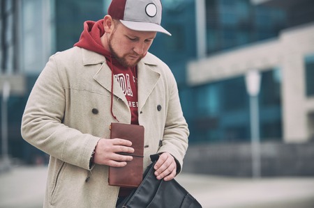 Young business man in casual clothes with leather notepad near of modern building.の写真素材