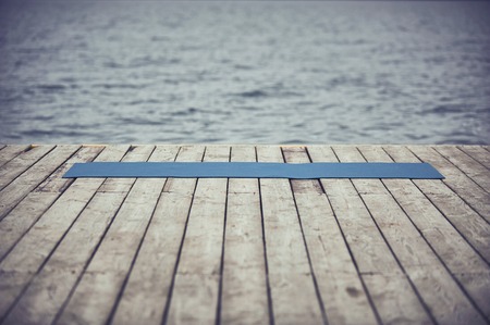 wooden deck near the lake and unrolled yoga mat on the floor