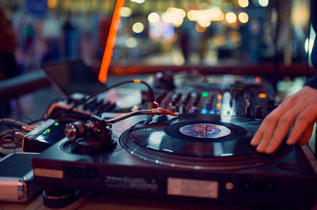 turntable, hand of dj on the vinyl record at night club. blured background.の写真素材