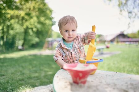 Toddler is playing in the sandbox on the green lawn. Sunny day.の写真素材
