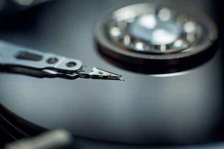 Disassembled hard disc. Read head, magnetic disk and spindle close-up.
