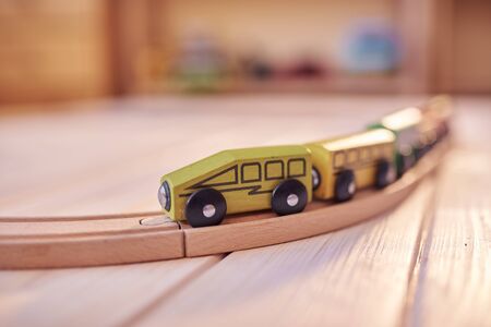 Wooden toy train on a track with defocused children's room in backdrop.の写真素材