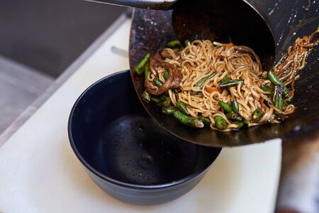 cooking process fried noodles with vegetables in the wok, traditional asian food.の写真素材