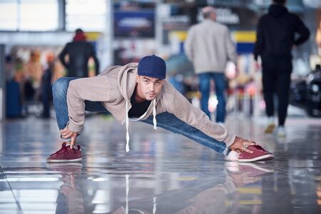 Young man practices yoga asana indoors in the public place.の写真素材