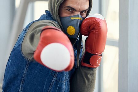 A guy in a protective mask and boxing gloves fights against viruses. Coronavirus covid-19 concept...